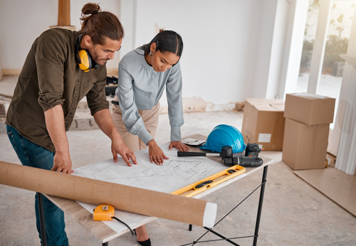 Shot of two young architects looking at building plans on site